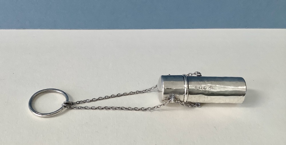 An antique Edwardian cylindrical sterling silver needle case featuring stamped silver hallmarks, attached to fine link chains and a suspension ring. View II