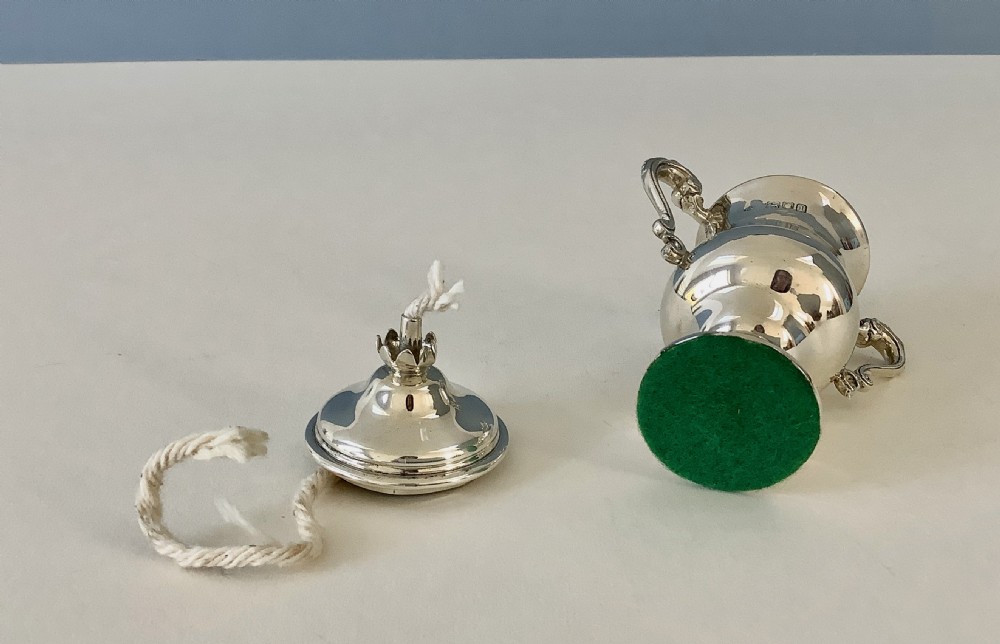 An antique urn-shaped sterling silver table lighter featuring twin scroll handles, a domed lid, and a protruding cotton wick. View III