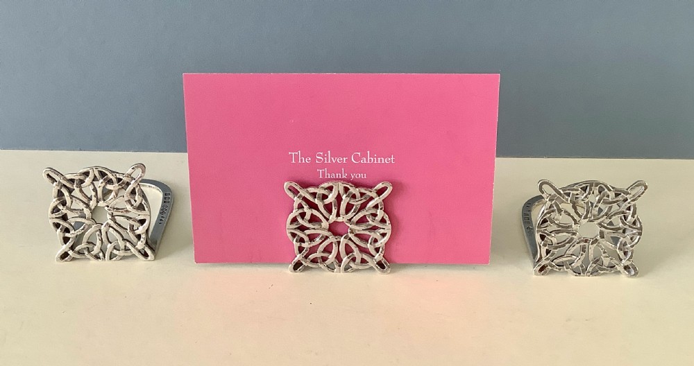 A set of three silver menu holders featuring square fronts decorated with intricate pierced Celtic knotwork patterns. View III