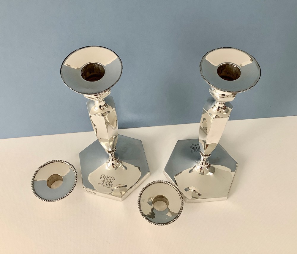 A pair of polished silver candlesticks with hexagonal bases, faceted columns, beaded rims, and engraved monograms. View III