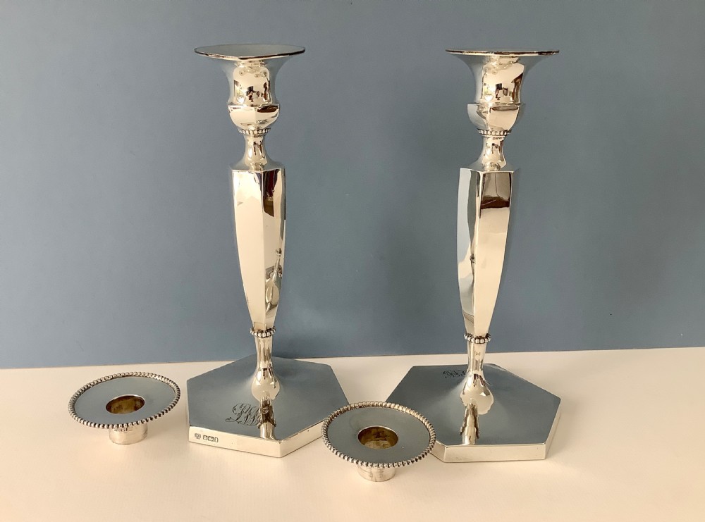 A pair of polished silver candlesticks with hexagonal bases, faceted columns, beaded rims, and engraved monograms. View V