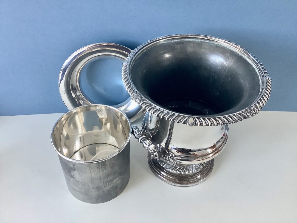 A Georgian silver-plated urn-shaped wine cooler featuring gadrooned borders, a pedestal base, and twin decorative side handles. View VI