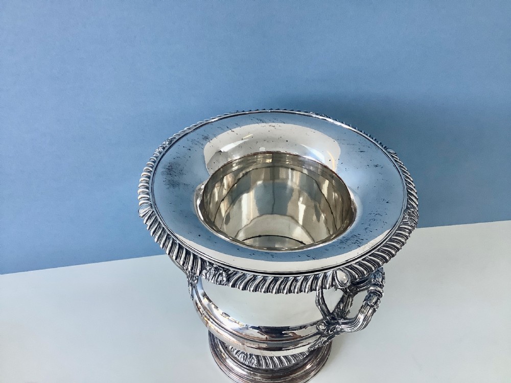 A Georgian silver-plated urn-shaped wine cooler featuring gadrooned borders, a pedestal base, and twin decorative side handles. View VII