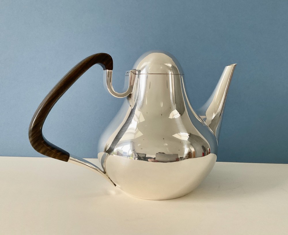 A polished silver Georg Jensen coffee pot featuring a bulbous teardrop body, seamless tapered spout, and a dark carved wooden handle. View II