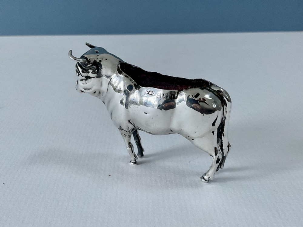 A small cast silver pin cushion shaped like a standing bull with a dark velvet insert fitted into its back. View VI