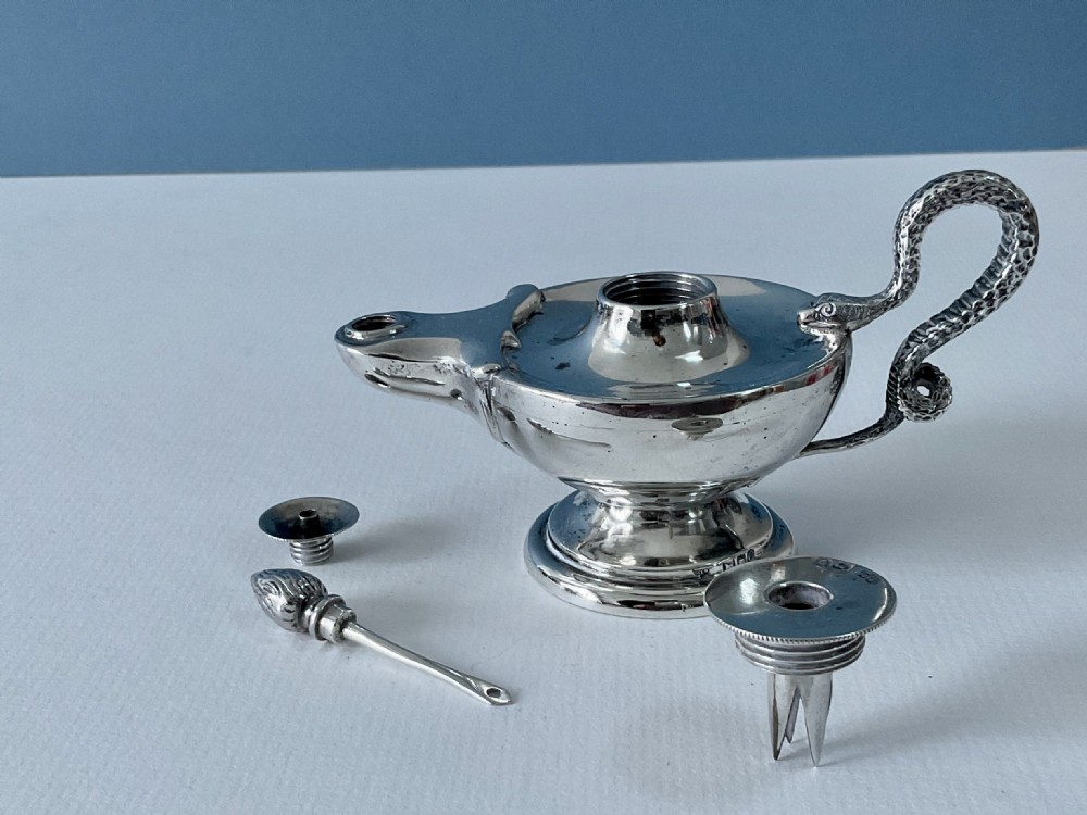 A polished silver table lighter modelled in the shape of an ancient oil lamp with a coiled serpent handle and a pedestal base. View VI
