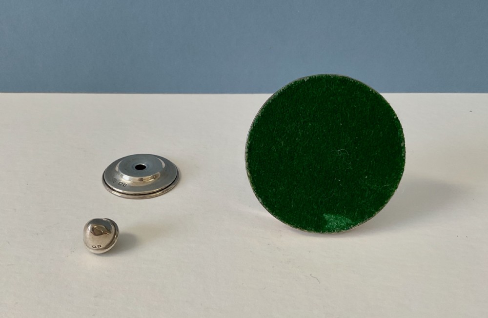 An antique silver cotton reel holder featuring a wooden spool wound with thread, set on a polished circular silver base and topped with a silver finial. View IV