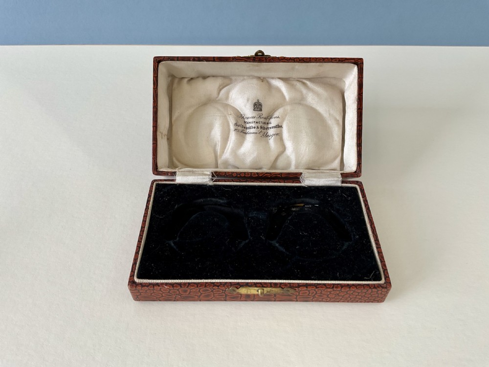 A pair of circular sterling silver napkin rings featuring engine-turned geometric patterns, beaded edges, and dark interior linings. View VII