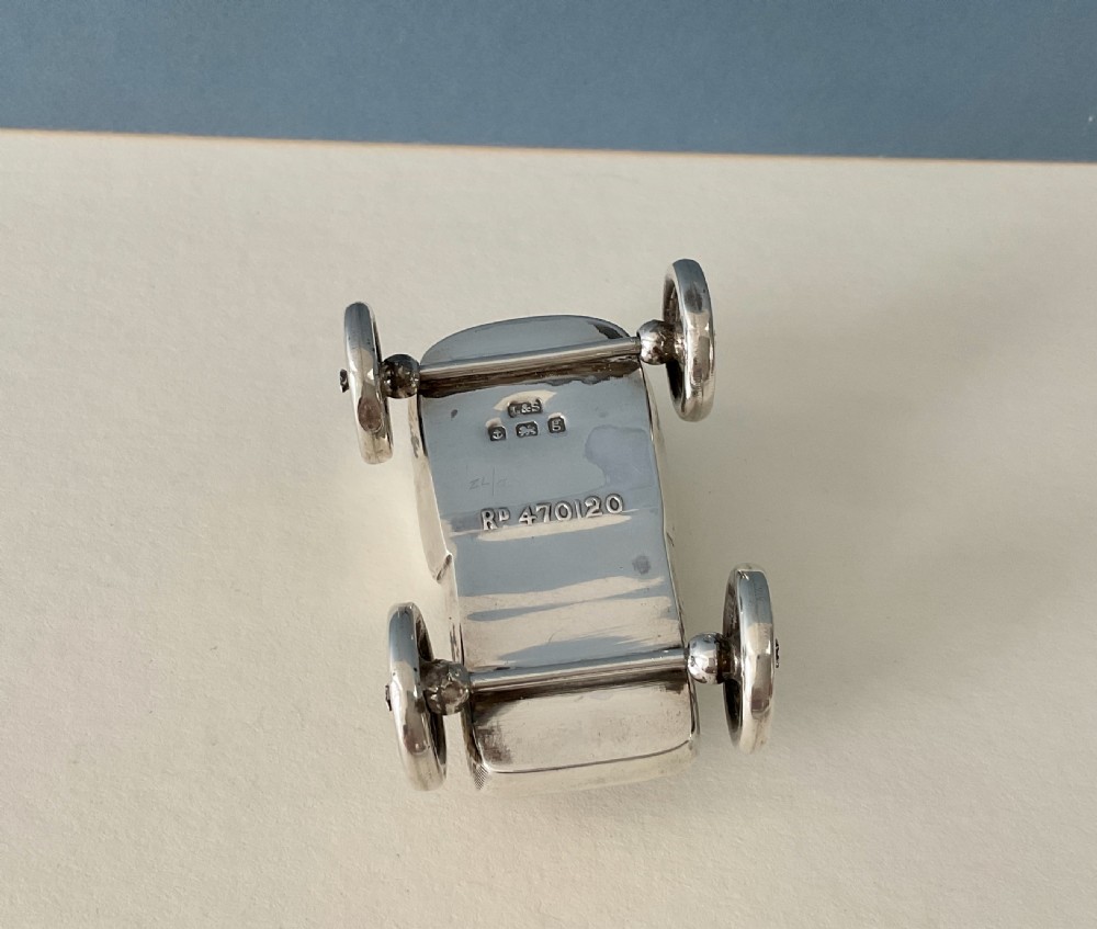 An antique sterling silver pin cushion shaped like an early motor car with detailed spoked wheels and a blue velvet seat insert. View III