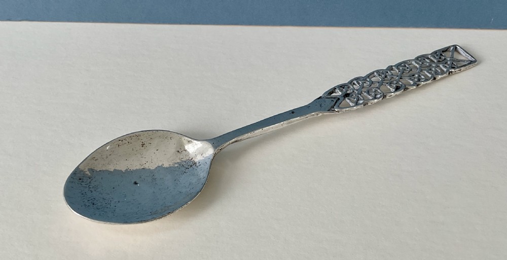 An Arts and Crafts sterling silver spoon with an oval bowl and an intricate pierced Celtic knotwork handle.