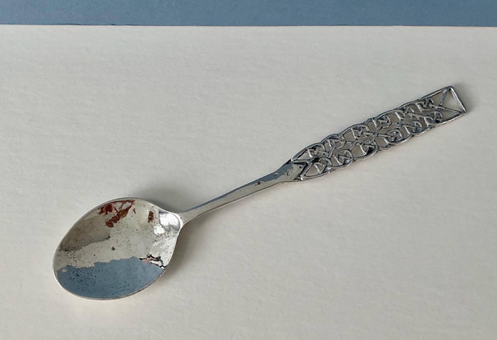 An Arts and Crafts sterling silver spoon with an oval bowl and an intricate pierced Celtic knotwork handle. View IX