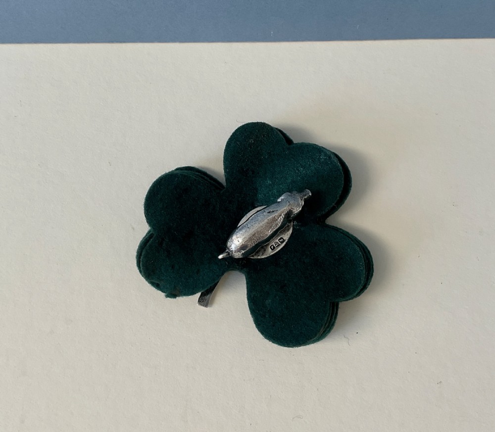 An antique silver pig finial mounted on stacked dark green clover-shaped felt pads. View III