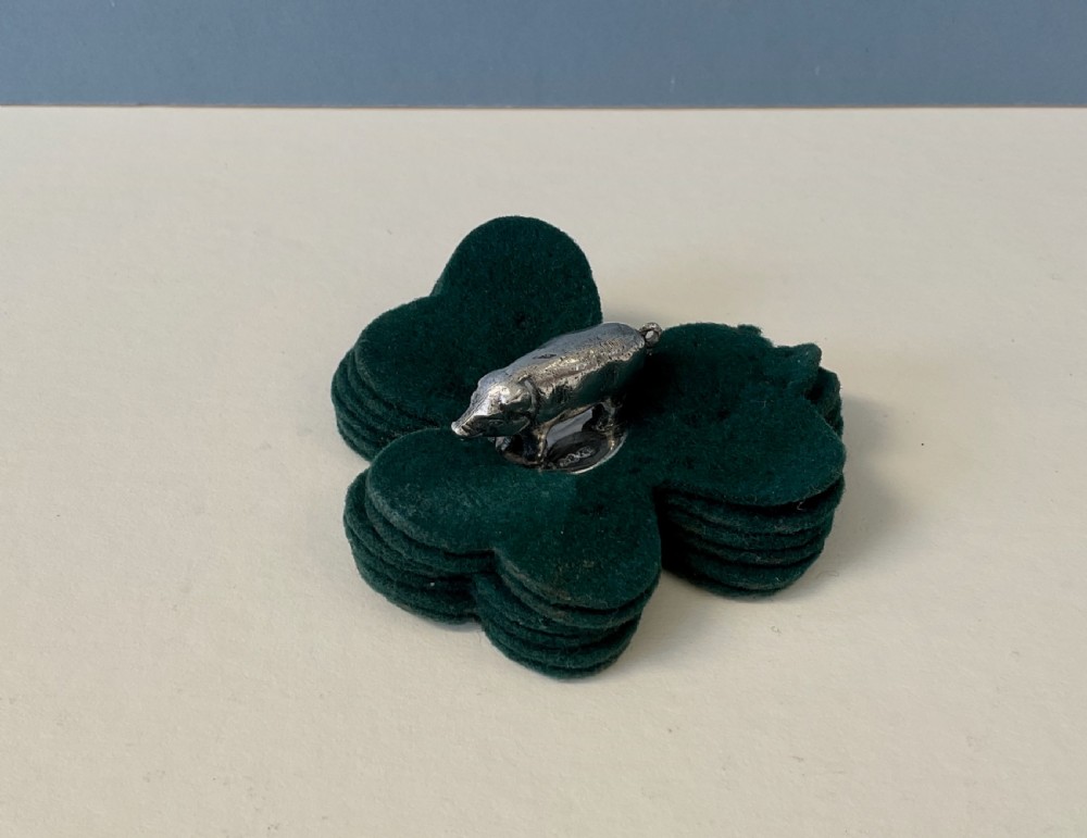 An antique silver pig finial mounted on stacked dark green clover-shaped felt pads. View IV