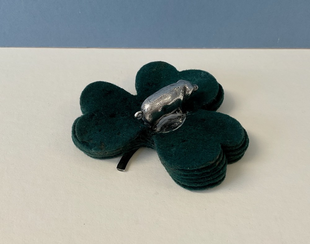 An antique silver pig finial mounted on stacked dark green clover-shaped felt pads. View VII