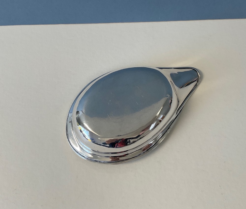 A shallow, elongated sterling silver pap boat featuring a smooth spout and a beaded rim pattern. View V
