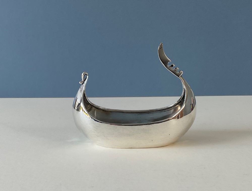 A polished silver decorative dish crafted in the shape of a Viking longship with a curved prow and stern.