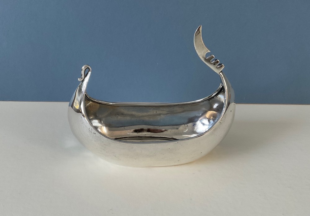 A polished silver decorative dish crafted in the shape of a Viking longship with a curved prow and stern. View III