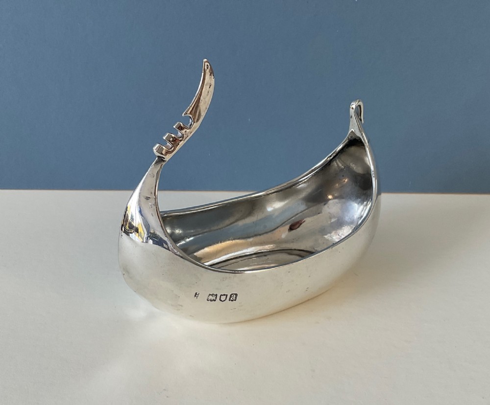 A polished silver decorative dish crafted in the shape of a Viking longship with a curved prow and stern. View V