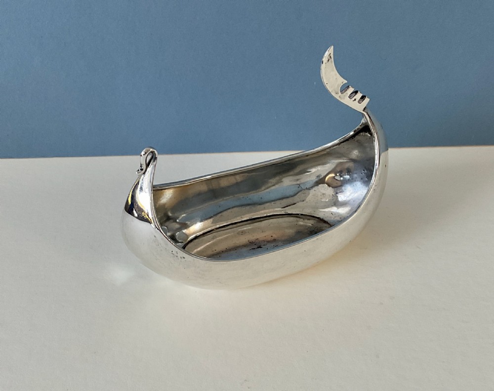 A polished silver decorative dish crafted in the shape of a Viking longship with a curved prow and stern. View VI