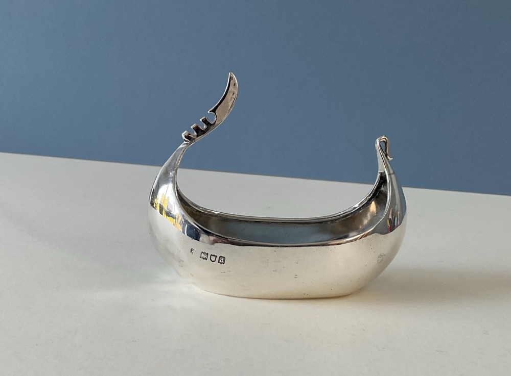 A polished silver decorative dish crafted in the shape of a Viking longship with a curved prow and stern. View VII
