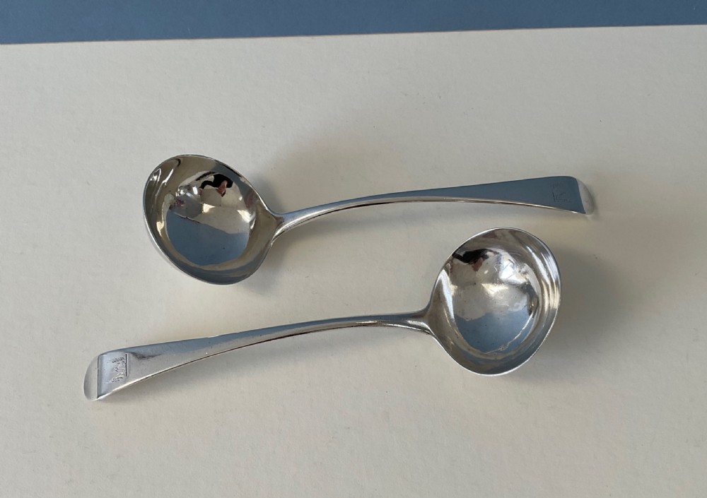 A pair of Georgian sterling silver ladles featuring curved handles with engraved crests and polished round bowls. View III