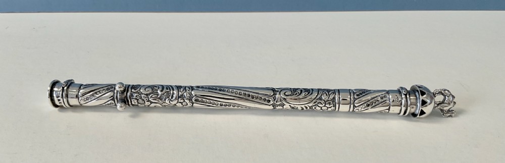 An antique cylindrical silver sealing wax holder decorated with intricate chased scrollwork, floral motifs, and a sculpted animal finial. View II