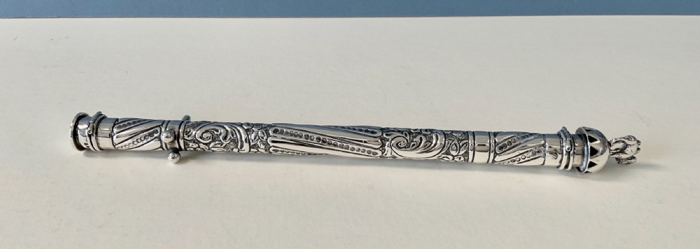 An antique cylindrical silver sealing wax holder decorated with intricate chased scrollwork, floral motifs, and a sculpted animal finial. View III