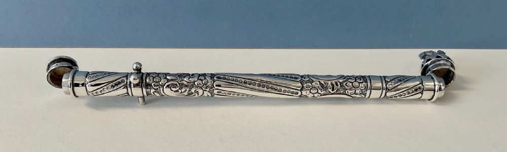 An antique cylindrical silver sealing wax holder decorated with intricate chased scrollwork, floral motifs, and a sculpted animal finial. View V