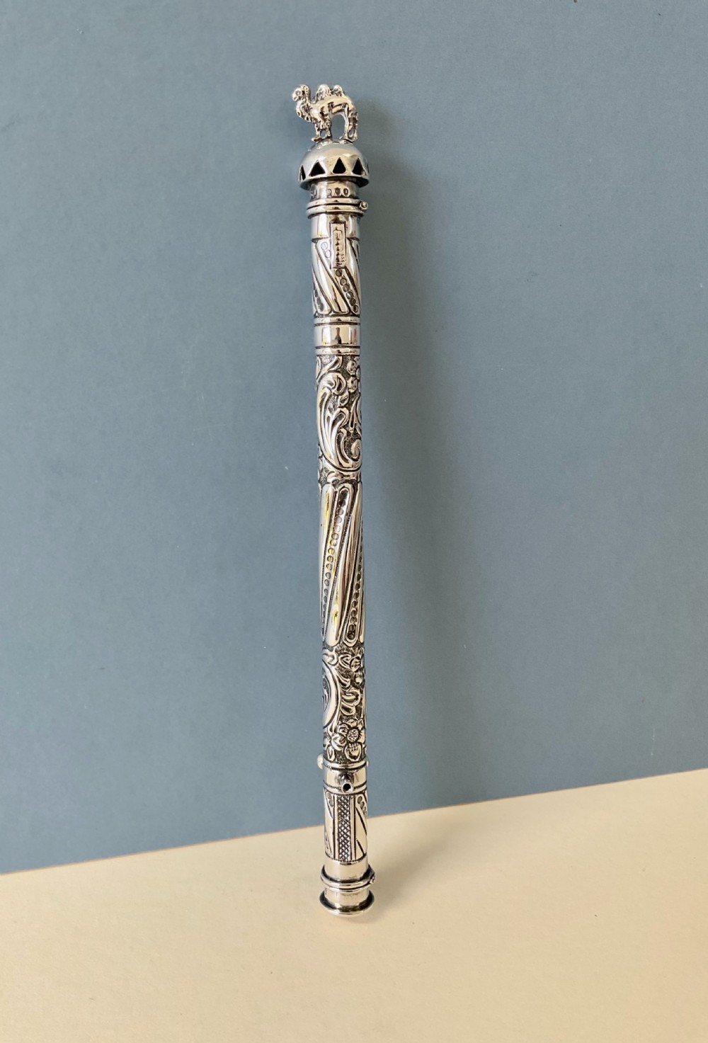 An antique cylindrical silver sealing wax holder decorated with intricate chased scrollwork, floral motifs, and a sculpted animal finial. View VII