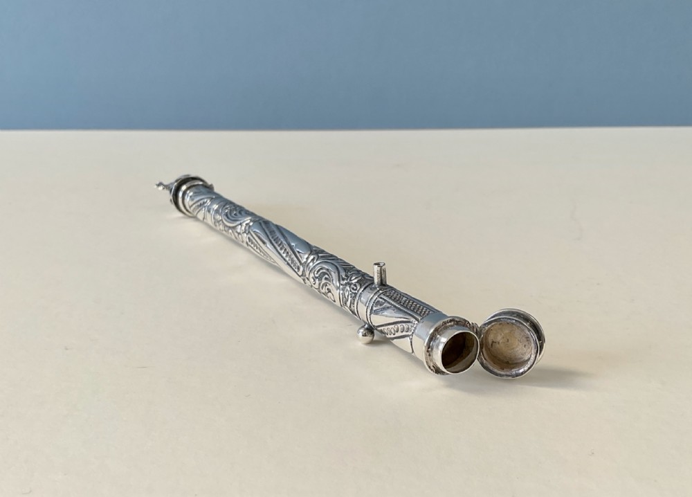 An antique cylindrical silver sealing wax holder decorated with intricate chased scrollwork, floral motifs, and a sculpted animal finial. View IX