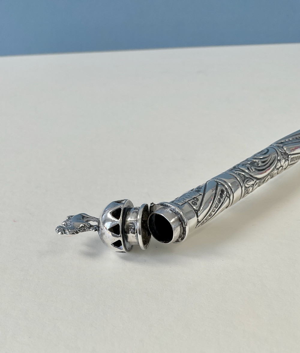 An antique cylindrical silver sealing wax holder decorated with intricate chased scrollwork, floral motifs, and a sculpted animal finial. View X