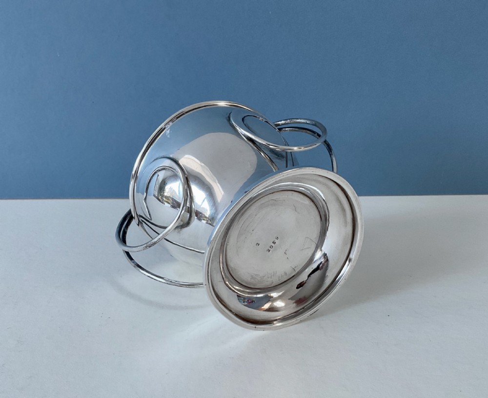 An antique silver Art Nouveau basket featuring a rounded bowl set on a pedestal base with a looping overhead handle. View V