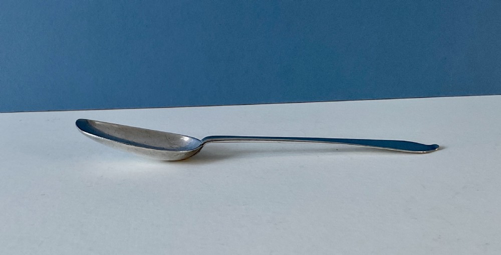 An antique silver spoon featuring an oval bowl and a slender stem terminating in a flared handle. View II