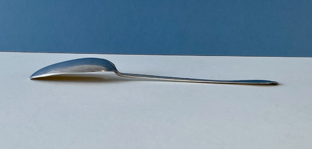 An antique silver spoon featuring an oval bowl and a slender stem terminating in a flared handle. View IV