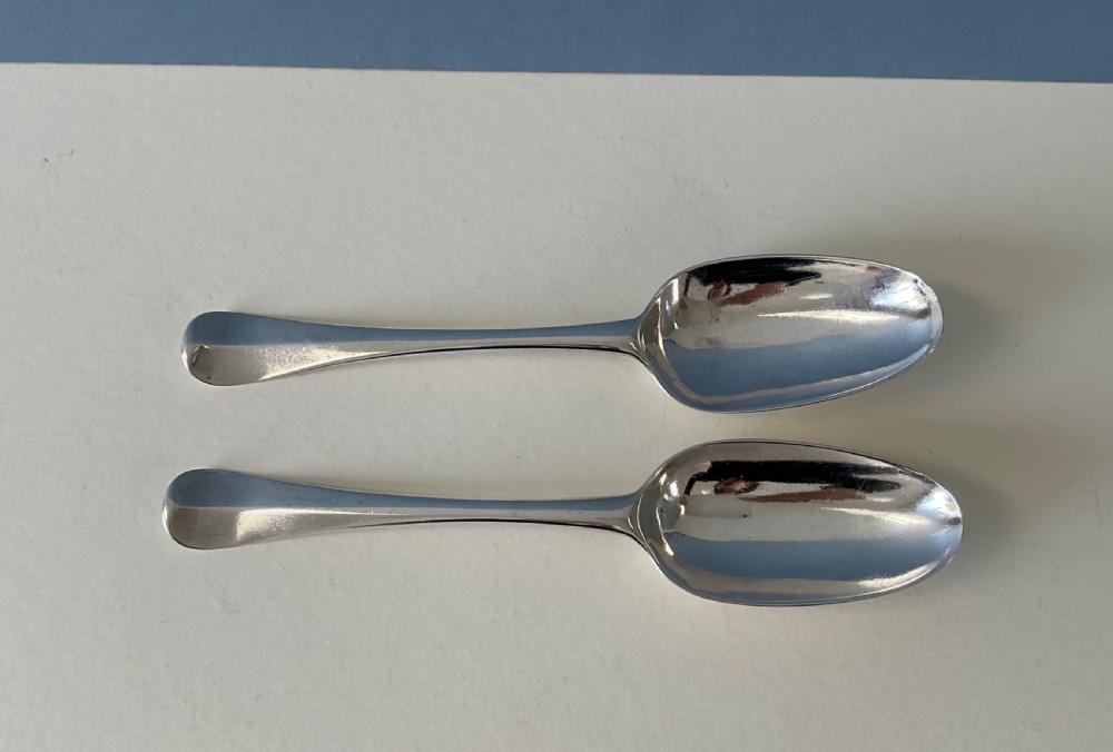 A pair of George I sterling silver spoons featuring elongated oval bowls and smooth Hanoverian stems with upturned terminals. View II