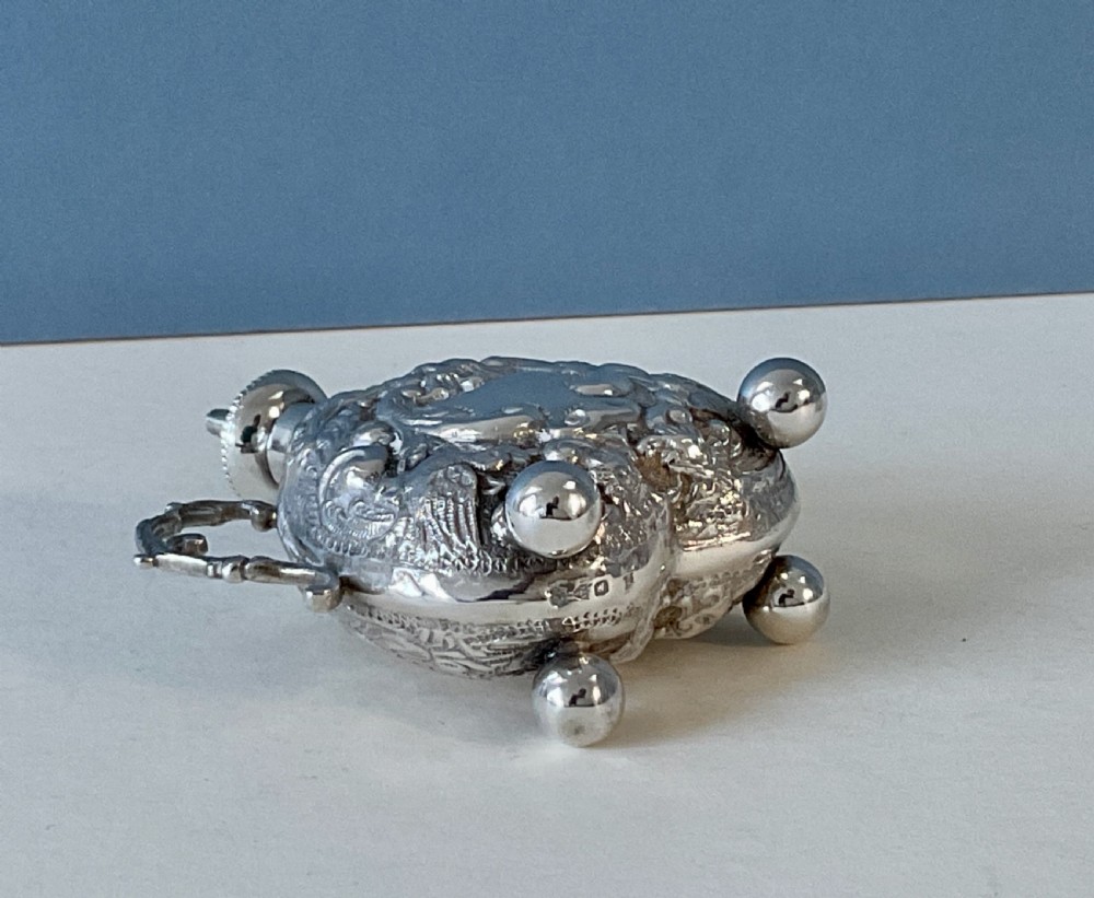 An antique Victorian silver table lighter featuring intricate repousse foliate scrollwork, twin handles, and spherical ball feet. View II