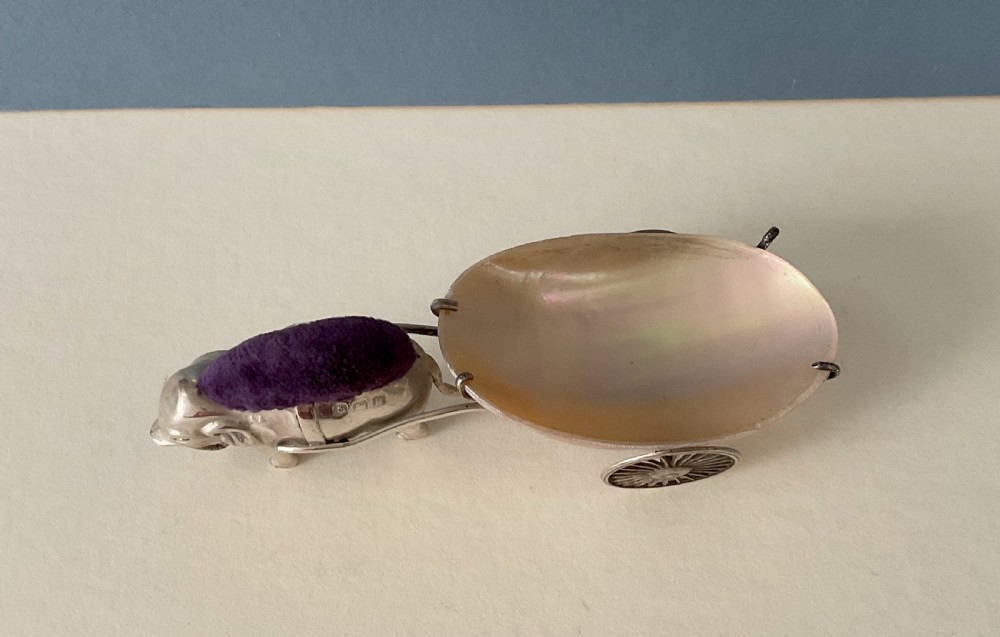 An antique solid silver novelty pin cushion formed as an elephant pulling a two-wheeled cart fitted with a polished shell dish. View VI