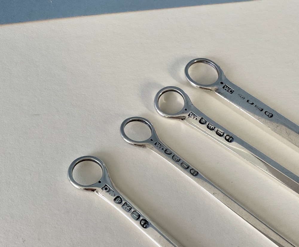 A set of four graduating solid silver skewers featuring simple ring terminals and stamped British hallmarks along the upper blades. View II