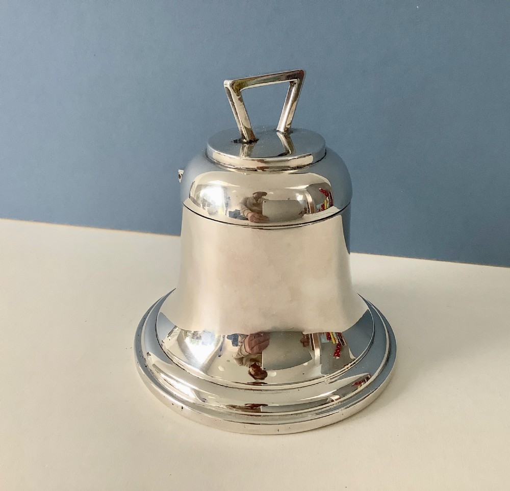 A polished silver Art Deco inkwell shaped like a bell with a geometric triangular handle on the lid.