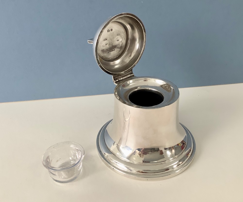 A polished silver Art Deco inkwell shaped like a bell with a geometric triangular handle on the lid. View III