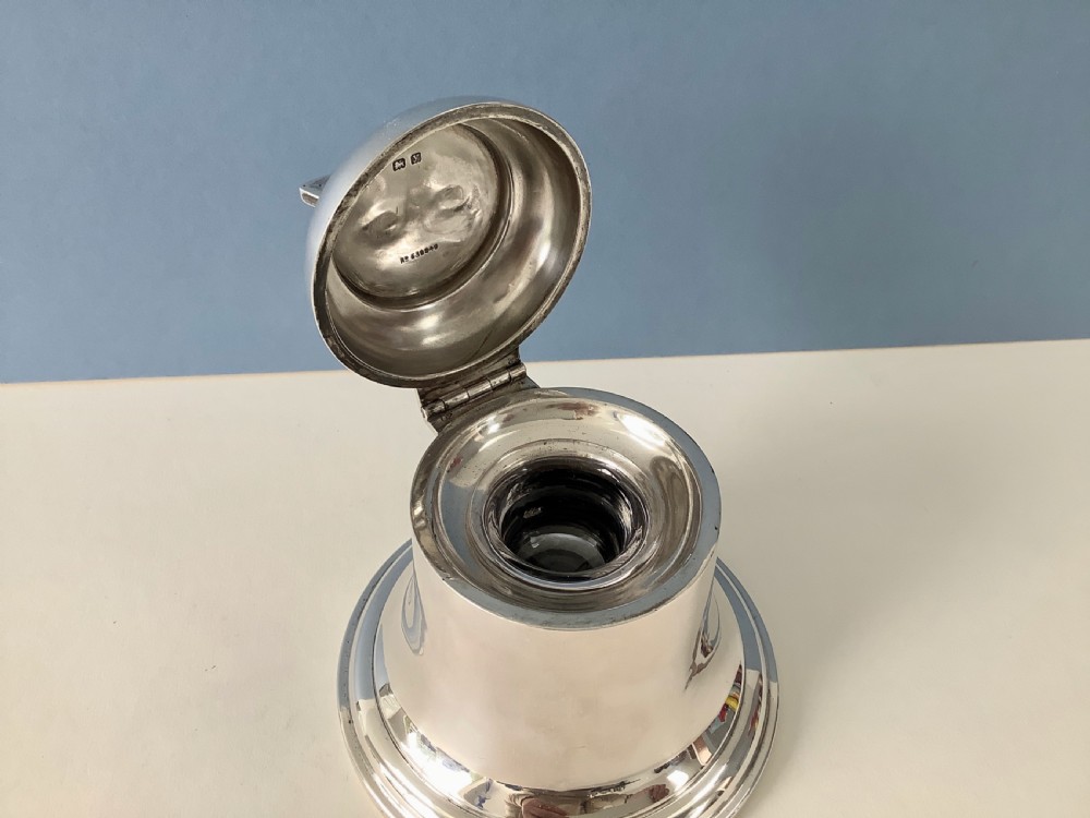 A polished silver Art Deco inkwell shaped like a bell with a geometric triangular handle on the lid. View IV