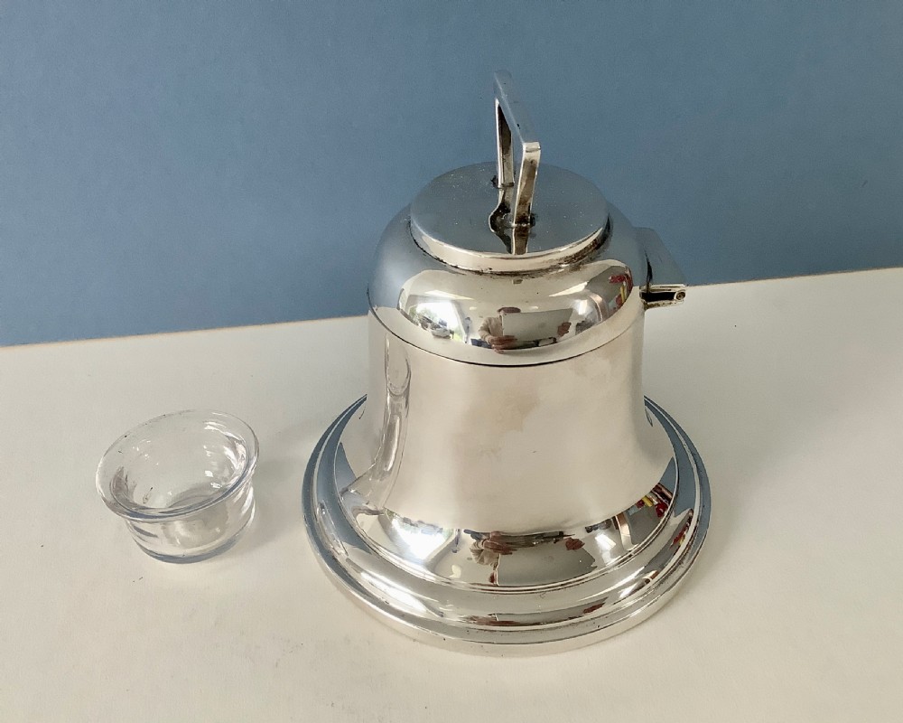 A polished silver Art Deco inkwell shaped like a bell with a geometric triangular handle on the lid. View V