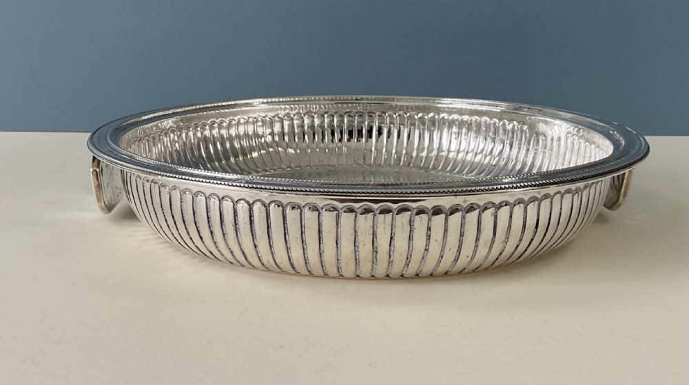 An ornate round Georgian solid silver entree dish featuring a domed lid decorated with repousse scrolling motifs, a figural finial, and a beaded rim. View VIII