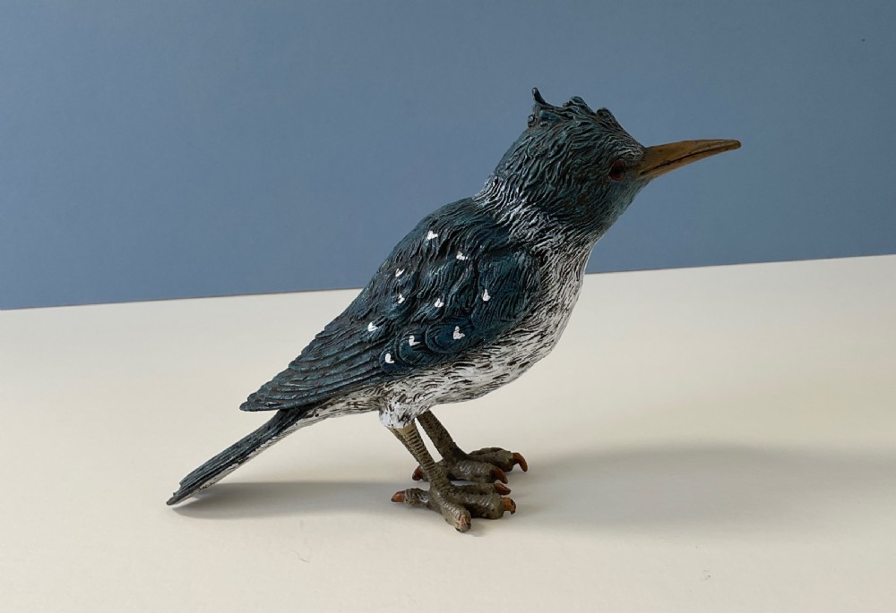 An antique cold-painted bronze figure of a crested kingfisher bird with blue, white, and bronze details standing on two legs. View VI