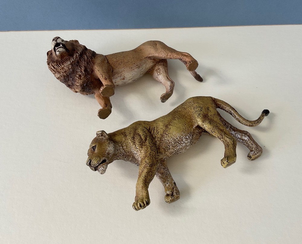 A pair of cold-painted bronze statuettes depicting a male lion and a lioness in realistic tawny brown tones. View II