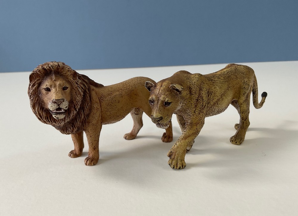 A pair of cold-painted bronze statuettes depicting a male lion and a lioness in realistic tawny brown tones. View VI