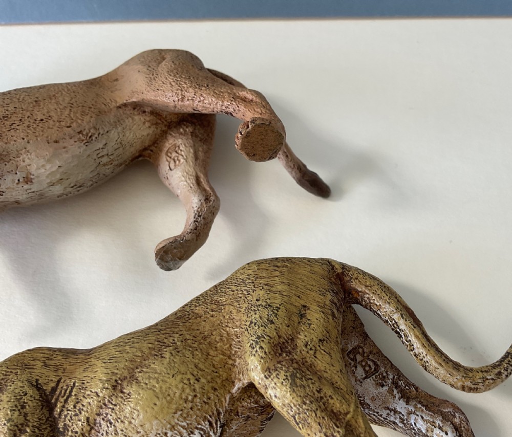 A pair of cold-painted bronze statuettes depicting a male lion and a lioness in realistic tawny brown tones. View VII