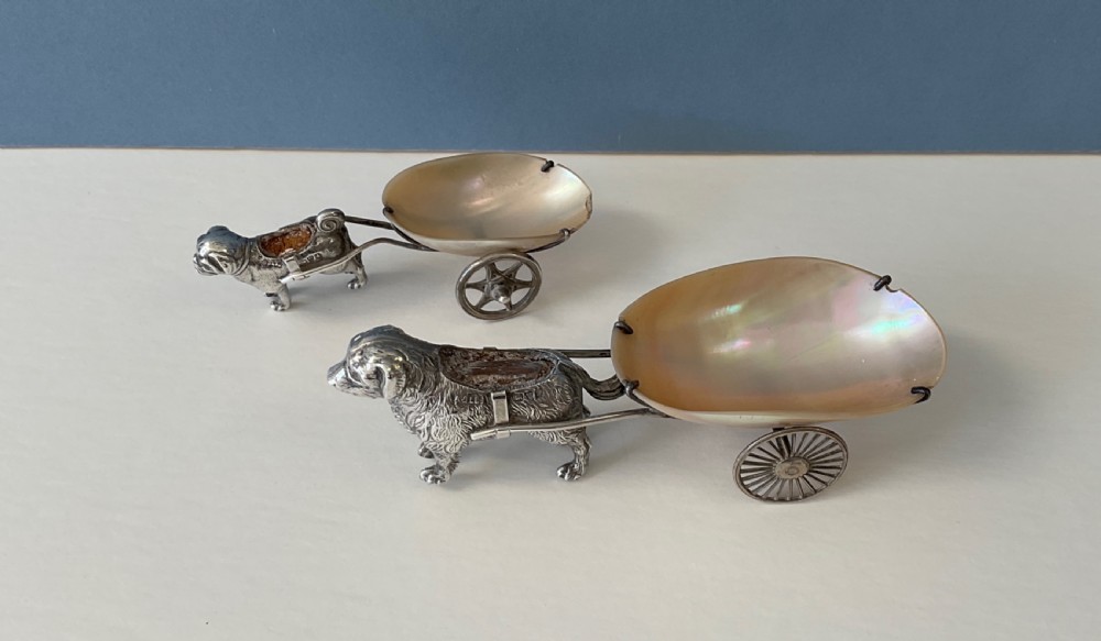 A pair of antique silver novelty pin cushions featuring detailed dog figures pulling mother-of-pearl shell carts on two wheels. View III