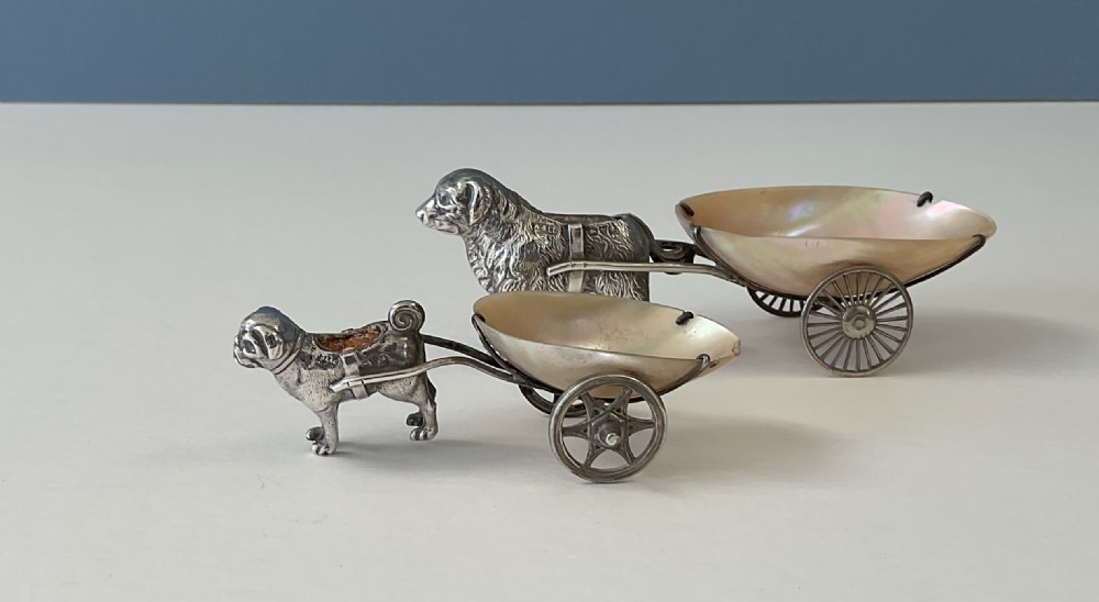A pair of antique silver novelty pin cushions featuring detailed dog figures pulling mother-of-pearl shell carts on two wheels. View IV
