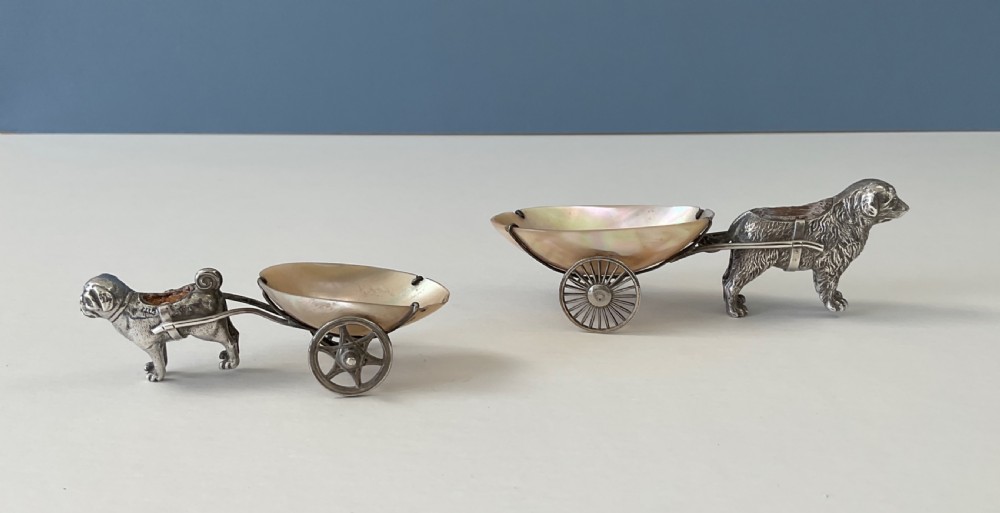 A pair of antique silver novelty pin cushions featuring detailed dog figures pulling mother-of-pearl shell carts on two wheels. View VII